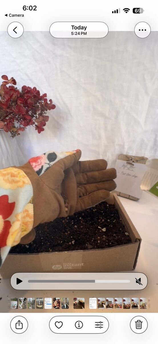 Floral gardening gloves working with soil on a linen-backed table.